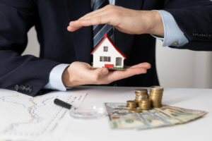 manos sosteniendo modelo de casa sobre un contrato de prestamo de hipoteca