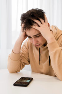 hombre joven viendo su celular ocn cara de preocupacion por estafa con yape falso